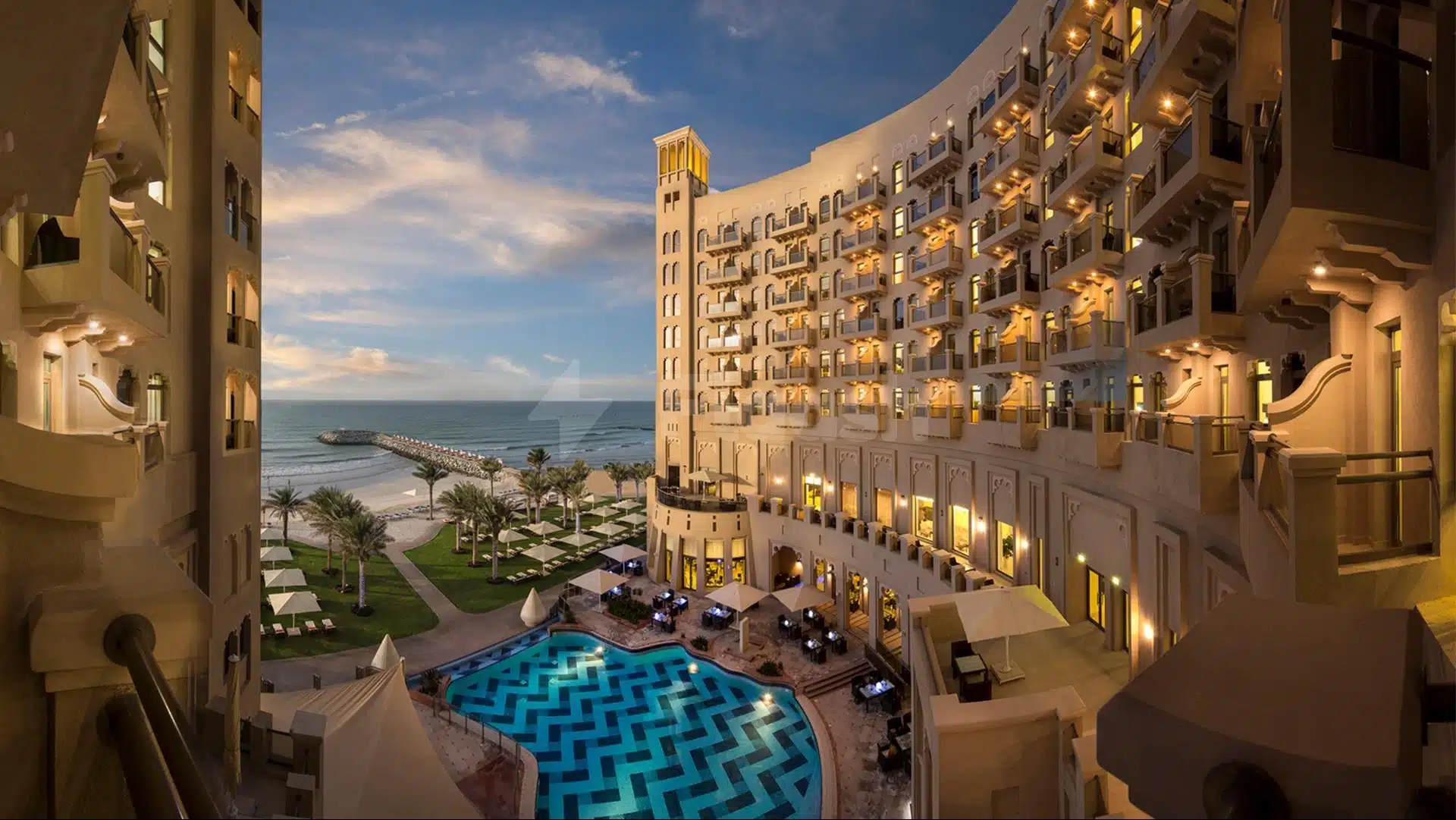 Pool deck at Bahi Ajman Palace Hotel, Ajman, with geometric-tiled pool and ocean view from balconies