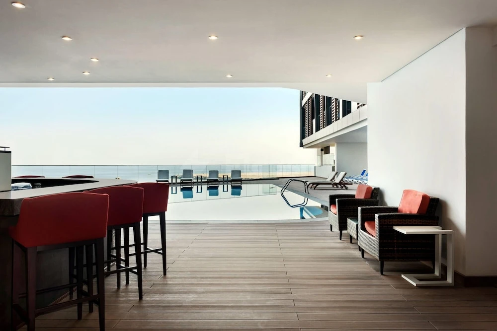 Poolside lounge at Wyndham Garden Ajman Corniche, Ajman, with red bar stools and ocean view