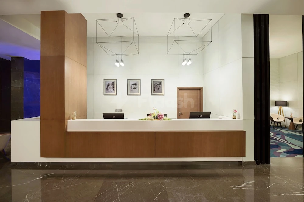 Reception area at Wyndham Garden Ajman Corniche, Ajman, with geometric pendant lights and framed artwork above the desk