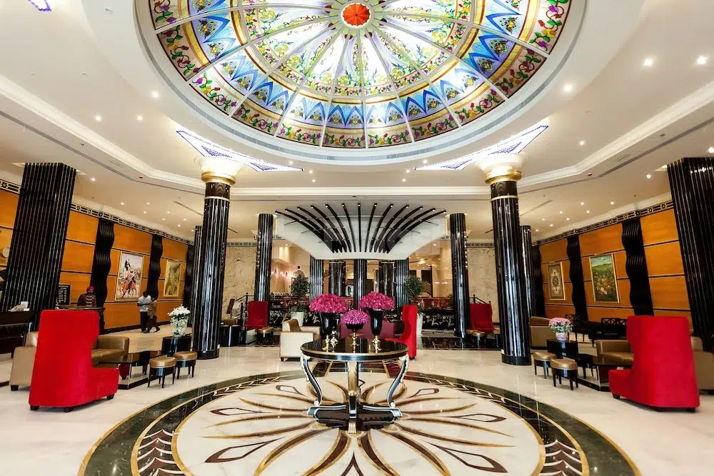 Grand lobby at Red Castle Hotel, Sharjah, featuring stained-glass dome and red velvet chairs