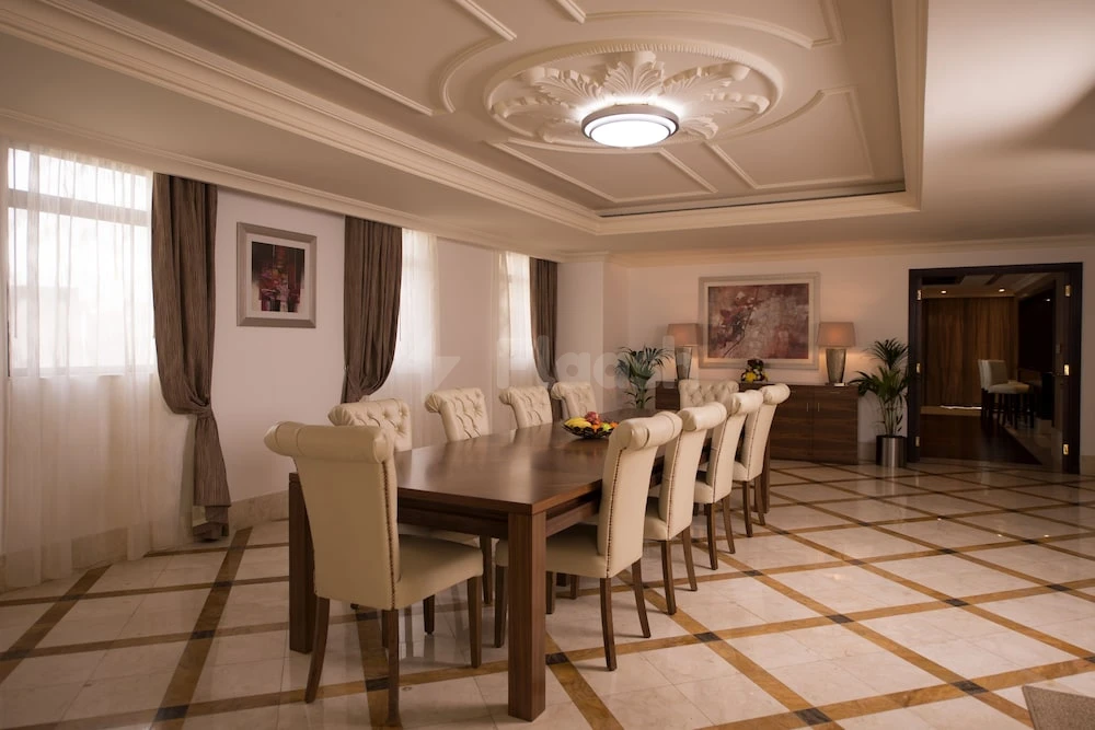 Dining room at Roda Amwaj Suites, Dubai, with a large wooden table surrounded by cream upholstered chairs under