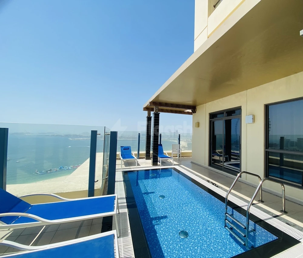 Private infinity pool at Roda Amwaj Suites, Dubai, with glass railings and blue lounge chairs facing the sea
