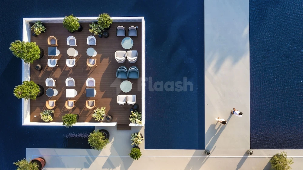 Outdoor lounge at Al Zorah Beach Resort, Ajman, featuring wooden deck with white chairs and potted greenery