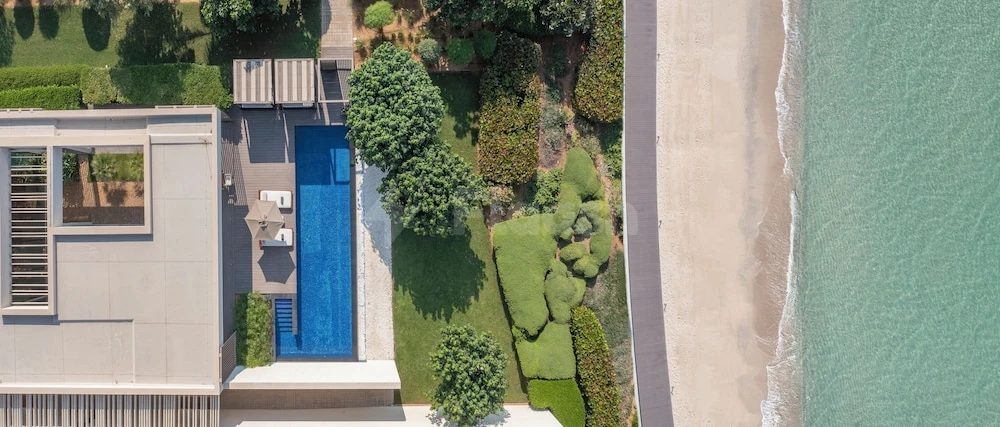Poolside terrace at Al Zorah Beach Resort, Ajman, featuring blue infinity pool adjacent to sandy beach and turquoise