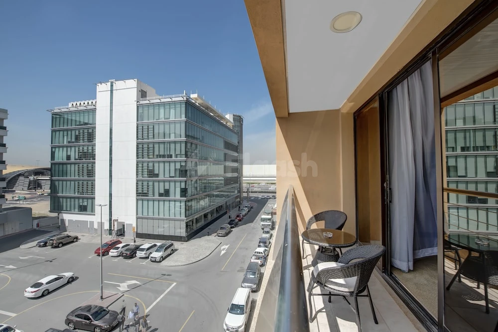 Balcony at Donatello Hotel Dubai, overlooking modern glass building and street with parked cars below
