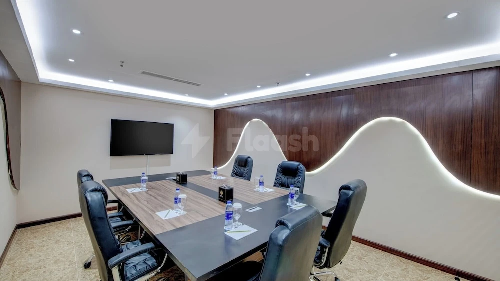 Conference room at Donatello Hotel Dubai, featuring a wavy illuminated wall panel and recessed ceiling lights