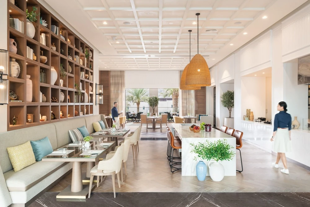 Dining area at Address Beach Resort Fujairah, Fujairah, featuring wood shelving with decor and a woven pendant light