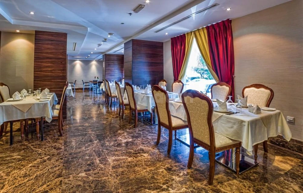 Dining area at Executive Suites - Abu Dhabi, Abu Dhabi, featuring polished marble floors and red-and-gold drapes