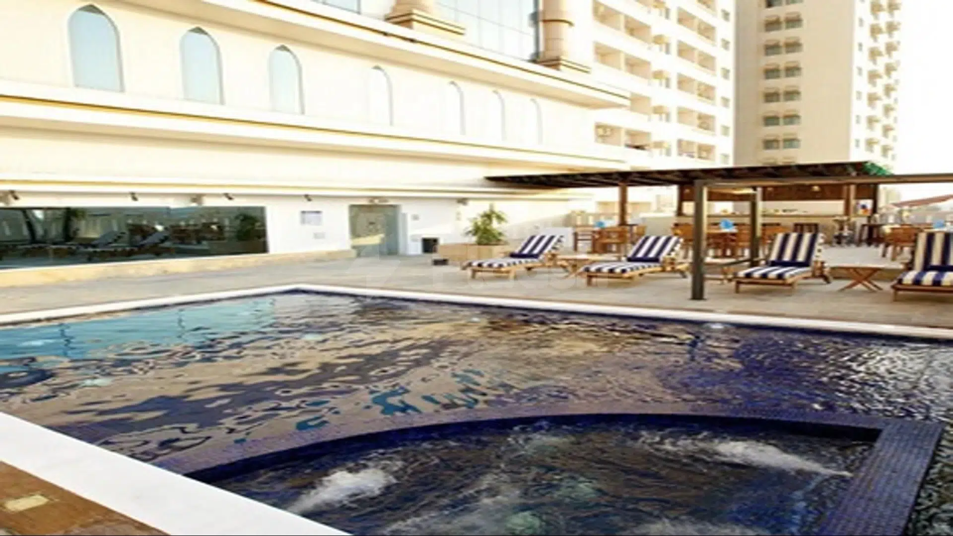 Outdoor pool at Mangrove Hotel, Ras Al Khaimah, with blue mosaic tiles and striped lounge chairs under