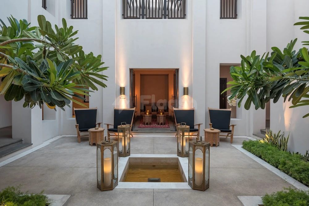 Courtyard lounge at The Chedi Al Bait, Sharjah, featuring central water feature and lanterns flanked by lush greenery