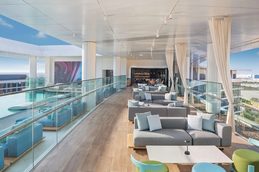 Rooftop lounge at The WB Abu Dhabi, Curio Collection by Hilton, with blue modular seating and glass railings