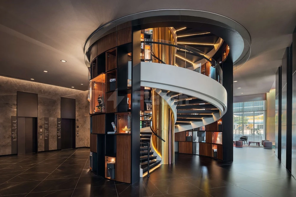 Spiral staircase at The WB Abu Dhabi, Curio Collection by Hilton, with illuminated bookshelves and polished stone floors