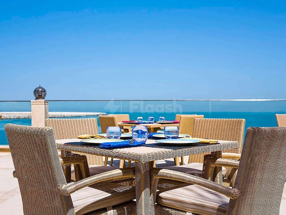 Outdoor dining terrace at Pullman Resort Al Marjan Island, Ras Al-Khaimah, with wicker furniture and sea view under