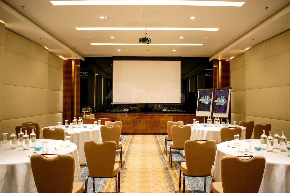Banquet hall at Radisson Blu Hotel Ajman, Ajman, with round tables set for dining and a large projection