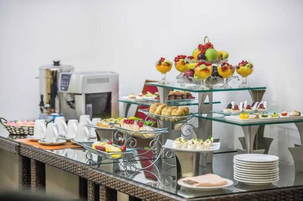 Buffet spread at Hotel Holiday International, Sharjah, featuring fruit cups and pastries on glass tiered stands