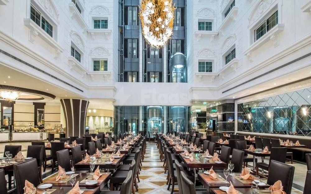 Grand dining hall at Hotel Holiday International, Sharjah, featuring a massive golden chandelier and multi-level white facade