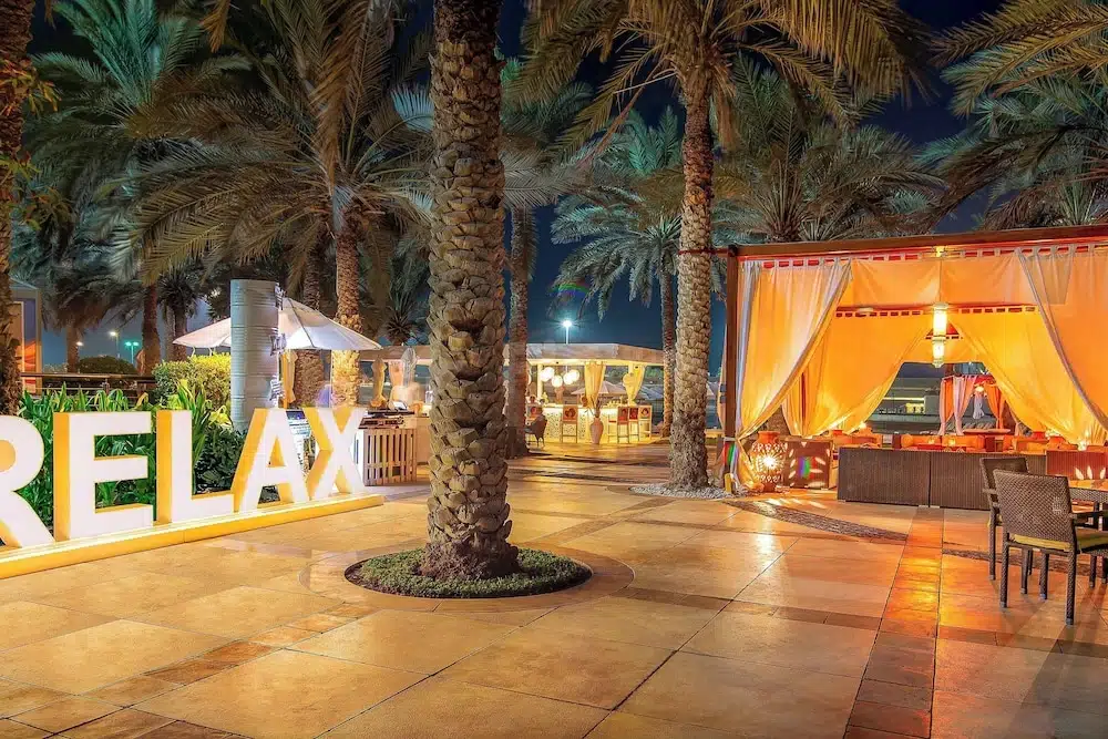 Outdoor lounge at Sheraton Abu Dhabi Hotel & Resort, Abu Dhabi, with illuminated "RELAX" sign and palm trees