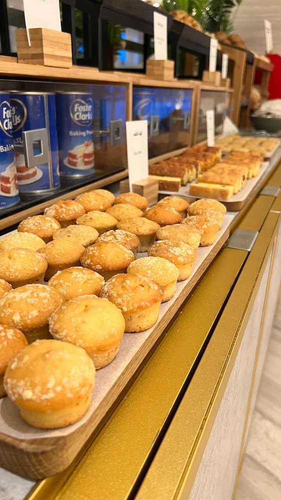 Buffet breakfast spread at DoubleTree by Hilton Fujairah City, Fujairah, featuring golden muffins on wooden trays with glass
