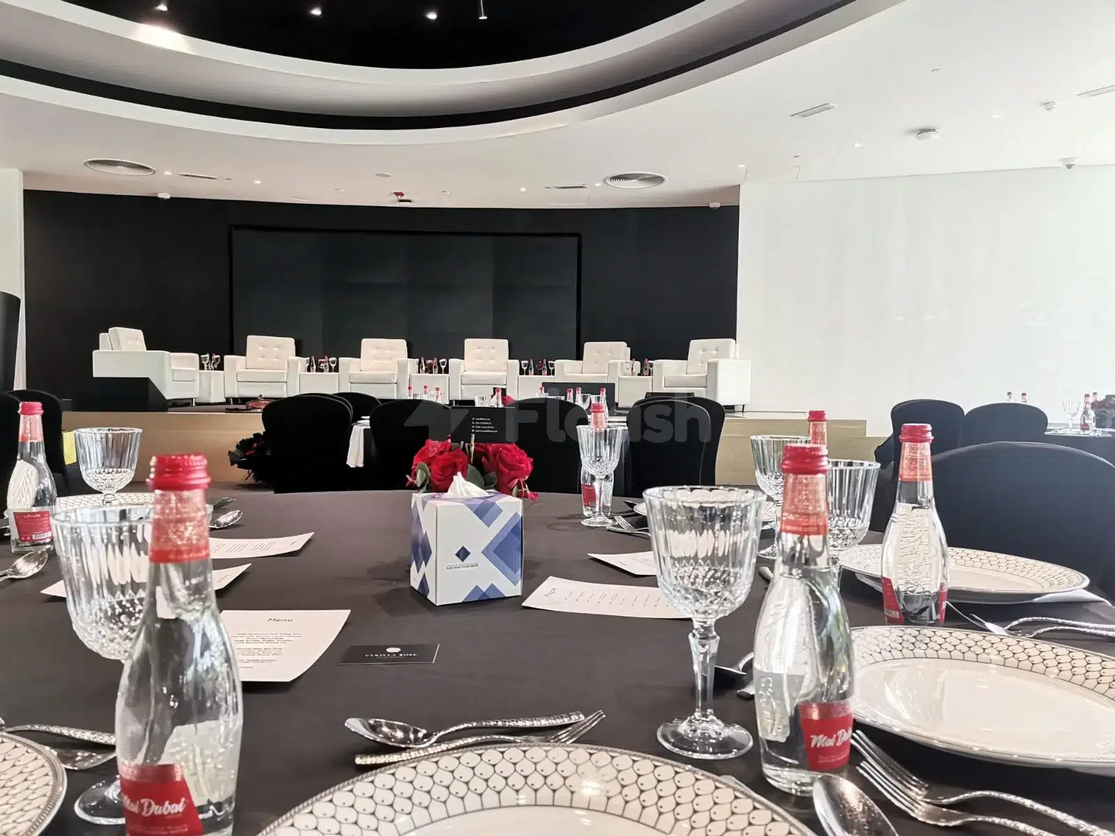 Boardroom at YourSpace, Aljada, Sharjah, with black chairs and red roses on tables under circular ceiling lights