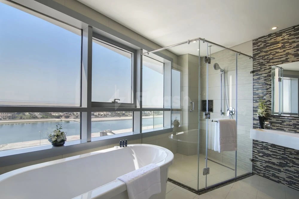 Bathroom at Pearl Rotana Capital Centre, Abu Dhabi, featuring freestanding tub and expansive window views over waterway