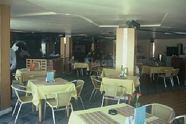 Dining area at Ajman Beach Hotel, Ajman, featuring tables with yellow cloths and chairs under warm lighting