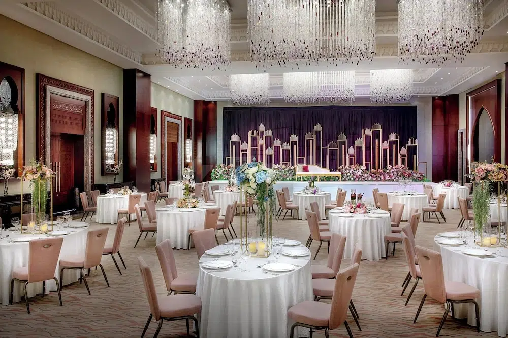Banquet hall at Ajman Saray, Ajman, with crystal chandeliers and floral centerpieces on round tables