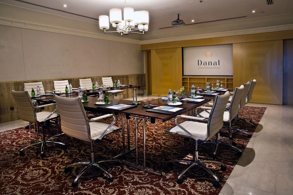 Conference room at Danat Jebel Dhanna Resort, Abu Dhabi, with polished tables and modern chairs under a chandelier