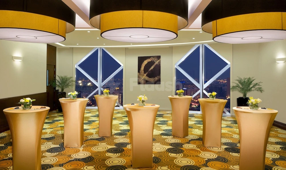 Banquet hall at City Seasons Towers Hotel, Dubai, features golden high tables and geometric ceiling lights overlooking city