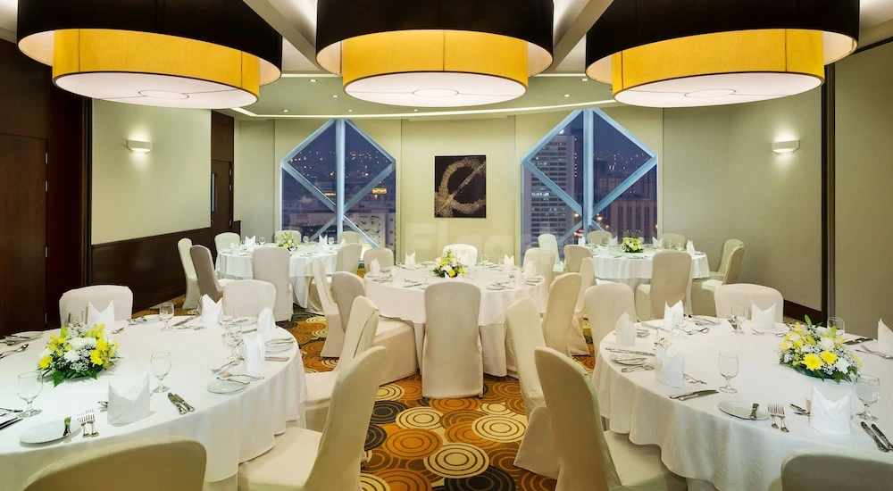 Banquet hall at City Seasons Towers Hotel, Dubai, with circular tables under yellow-and-black pendant lights and geometric