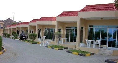 Beiso, a row of beachfront bungalows at Holiday Beach Motel, Fujairah, with365, with red-tiled roofs and glass doors