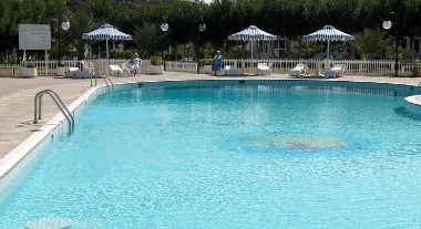 Poolside lounge at Holiday Beach Motel, Fujairah, with blue umbrellas and white railings along the edge