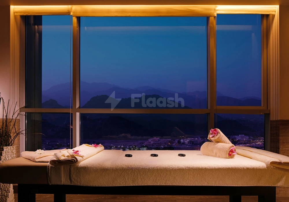 Spa treatment room at Royal M Hotel Fujairah, Fujairah, featuring mountain view and heated stones on towel-draped table
