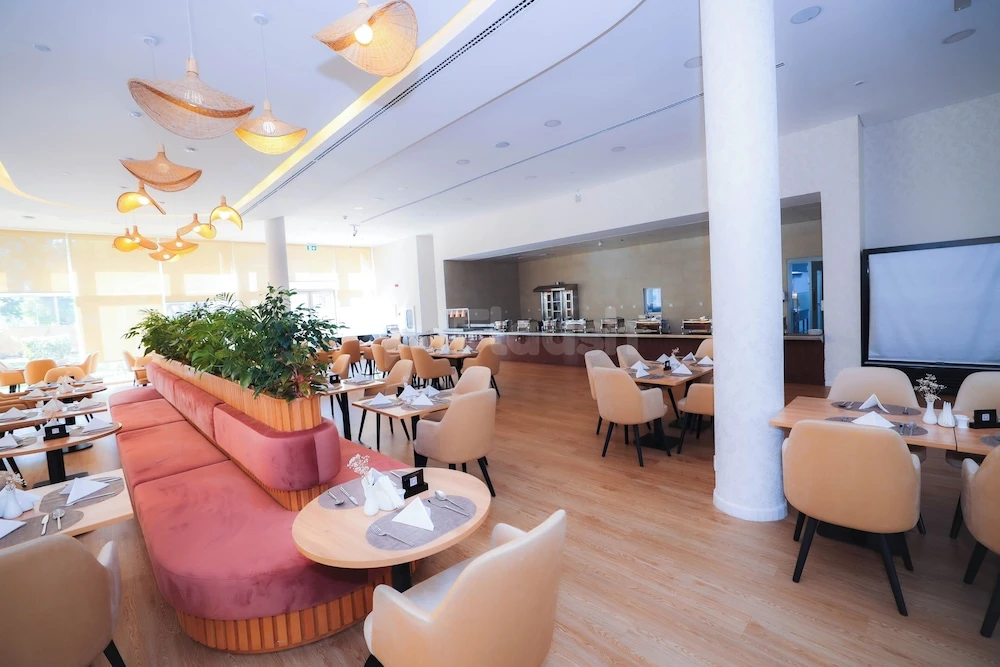 Modern dining space at eStay Hotel Dubai, Dubai, with pink upholstered booths and warm wooden tables.25