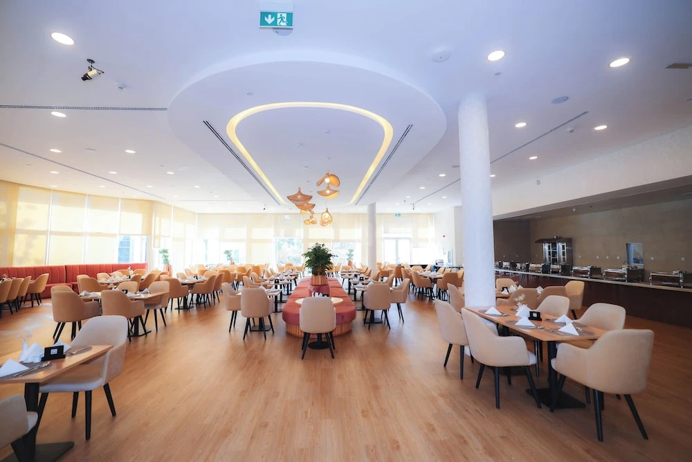 Modern dining space at eStay Hotel Dubai, Dubai, with sleek wooden tables and cream chairs arranged neatly under