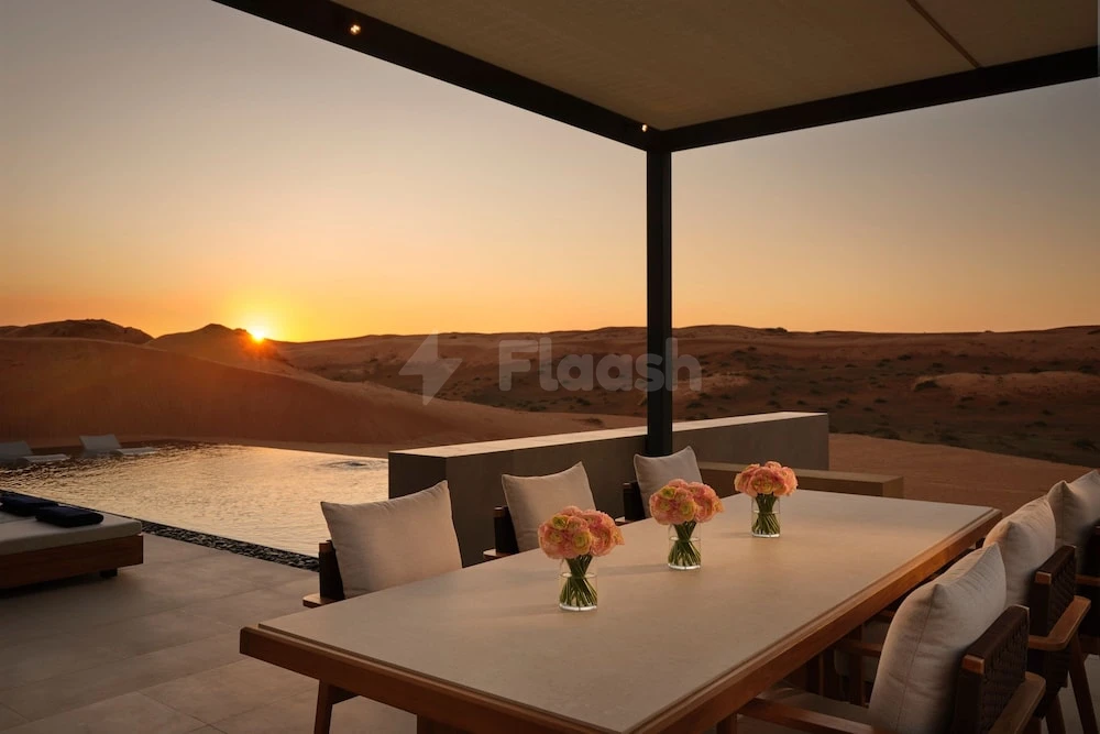 Dining terrace at The Ritz-Carlton Ras Al Khaimah, Al Wadi Desert, with sunset over desert dunes and infinity