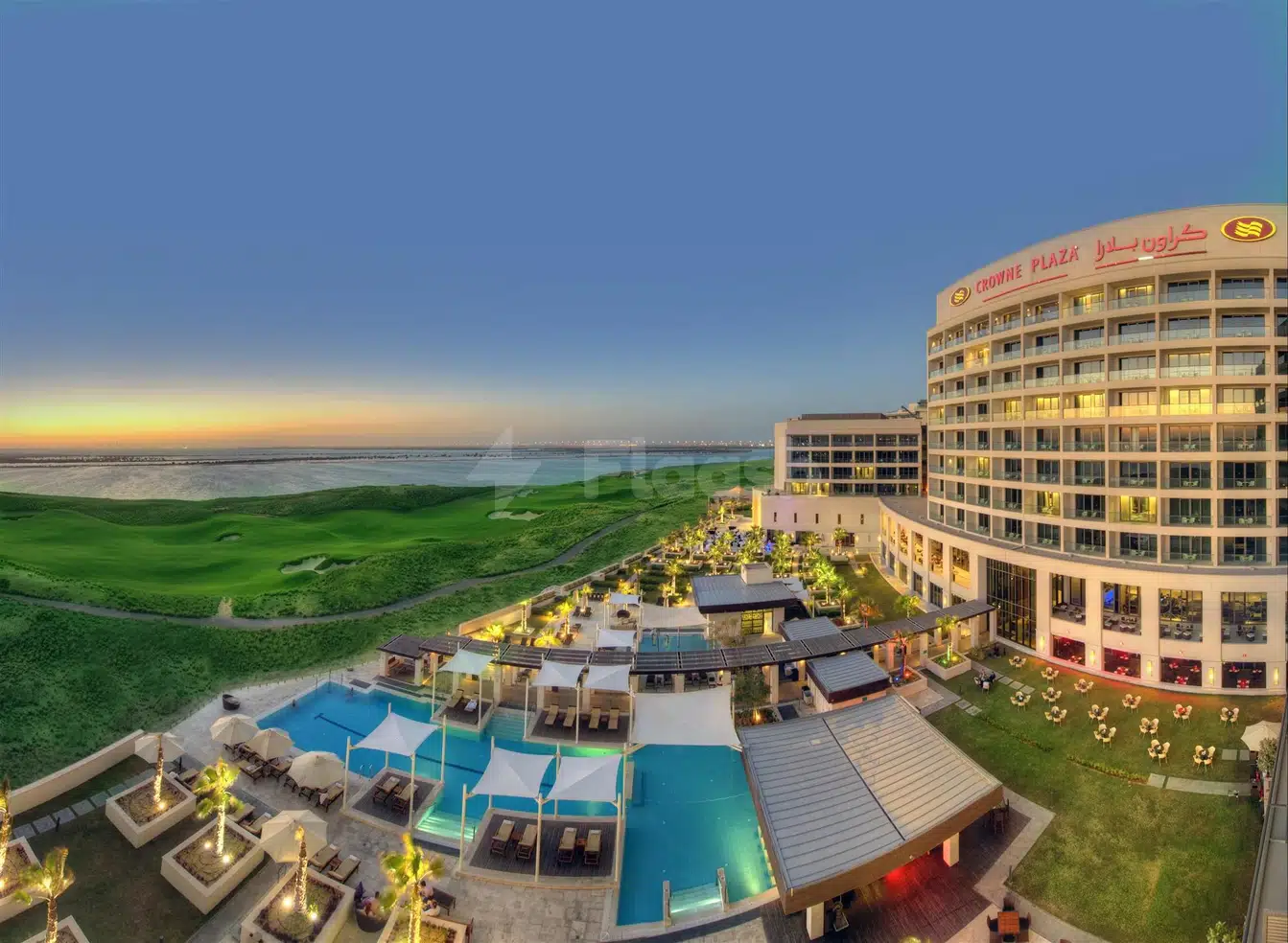 Outdoor swimming pool area at Crowne Plaza Abu Dhabi - Yas Island, featuring illuminated lounge chairs and palm trees