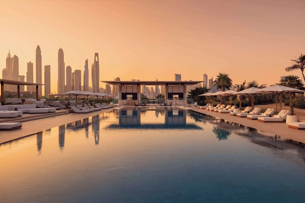 Infinity pool at One&Only The Palm, Dubai, reflecting skyline and lounge chairs under golden twilight sky