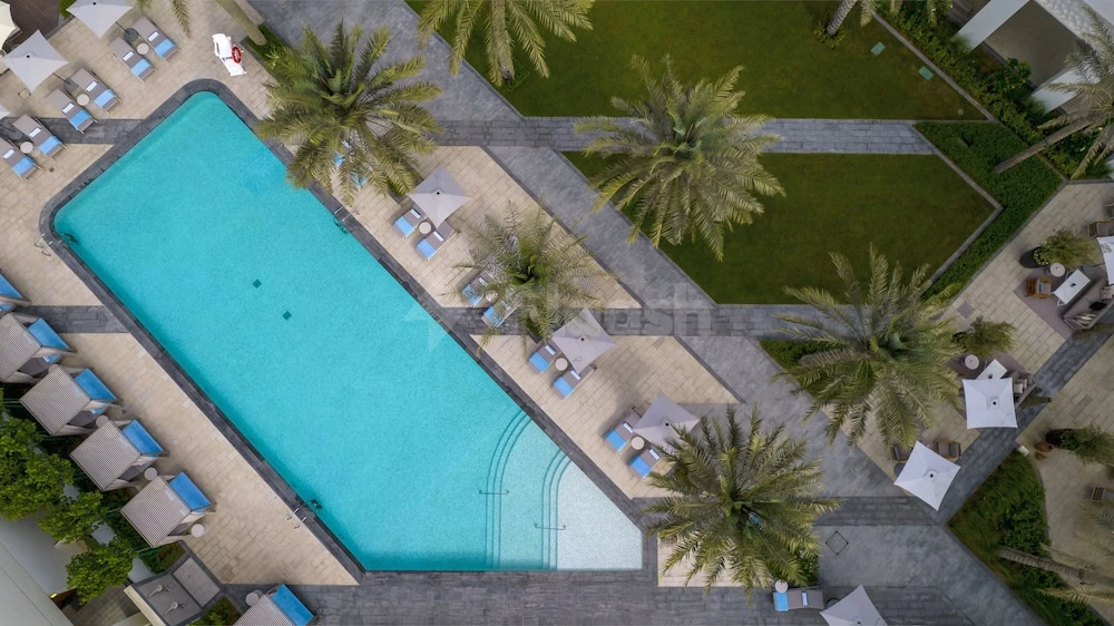 Outdoor pool at Palace Beach Resort Fujairah, Fujairah, surrounded by palm trees and lounge chairs