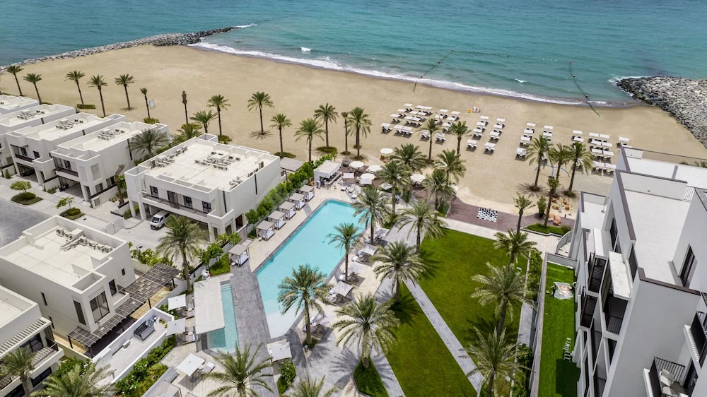 Poolside terrace at Palace Beach Resort Fujairah, Fujairah, with palm-lined beach and turquoise sea view