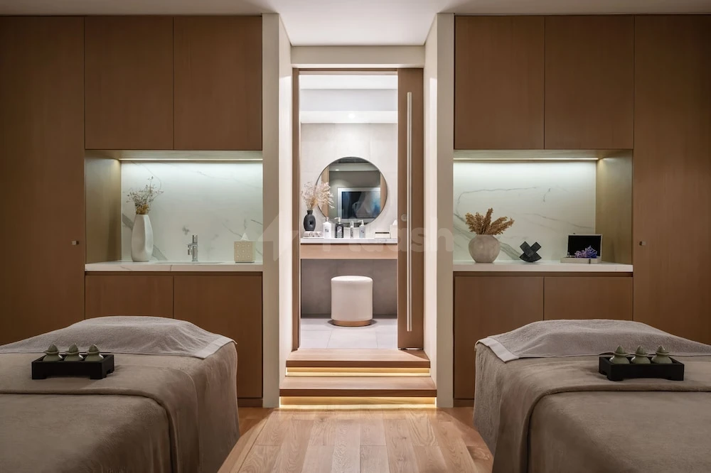 Spa treatment room at Palace Beach Resort Fujairah, Fujairah, featuring wooden cabinetry and illuminated niches with decorative white