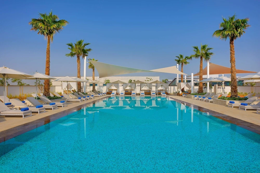 Outdoor pool area at DoubleTree by Hilton Abu Dhabi Yas Island Residences, Abu Dhabi, with palm trees lining