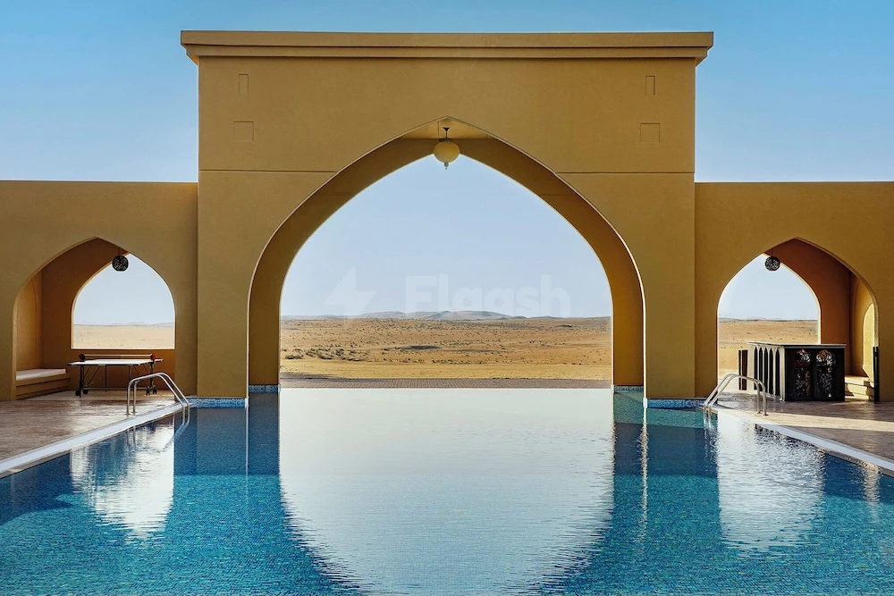 Infinity pool at Aldhafra Resort, Vignette Collection, an IHG Hotel, Abu Dhabi, framed by arched sand-colored walls reflecting