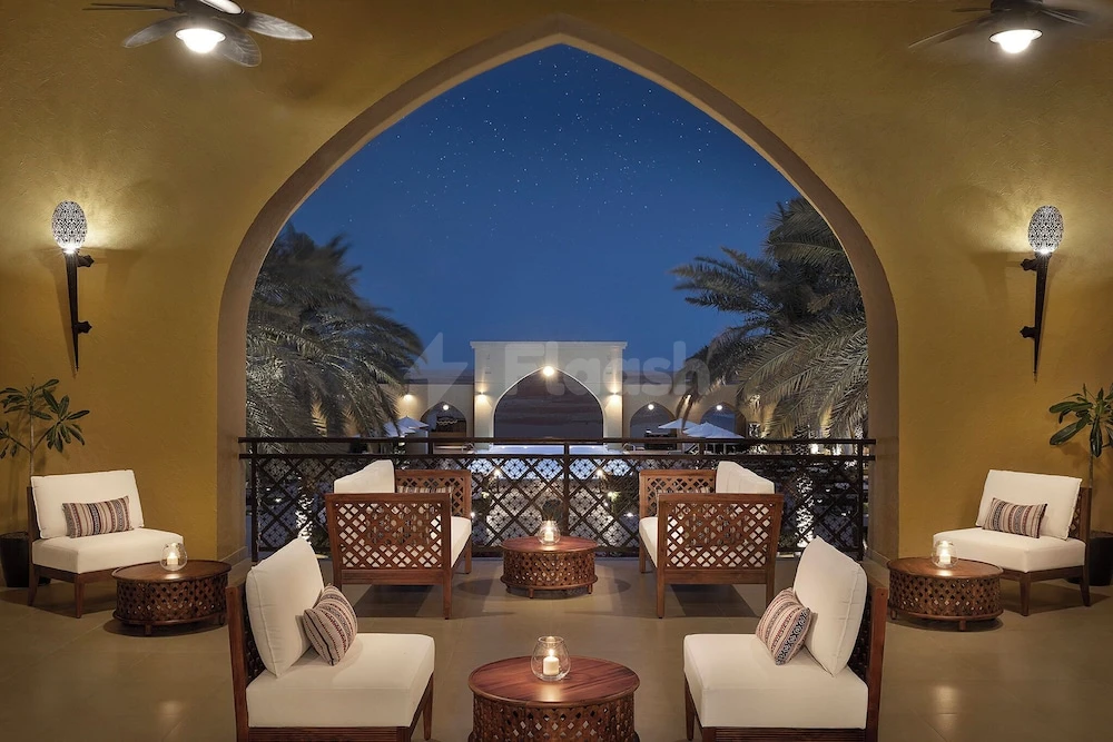 Terrace lounge at Aldhafra Resort, Abu Dhabi, framed by arched walls and starlit palms