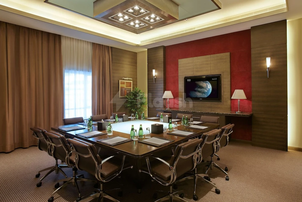 Conference room at Nour Arjaan by Rotana, Fujairah, with red accent wall and ceiling-mounted lights