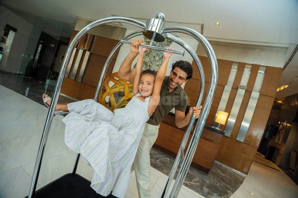 Lobby at Nour Arjaan by Rotana - Fujairah, Fujairah, with polished marble floors and modern luggage cart sculpture