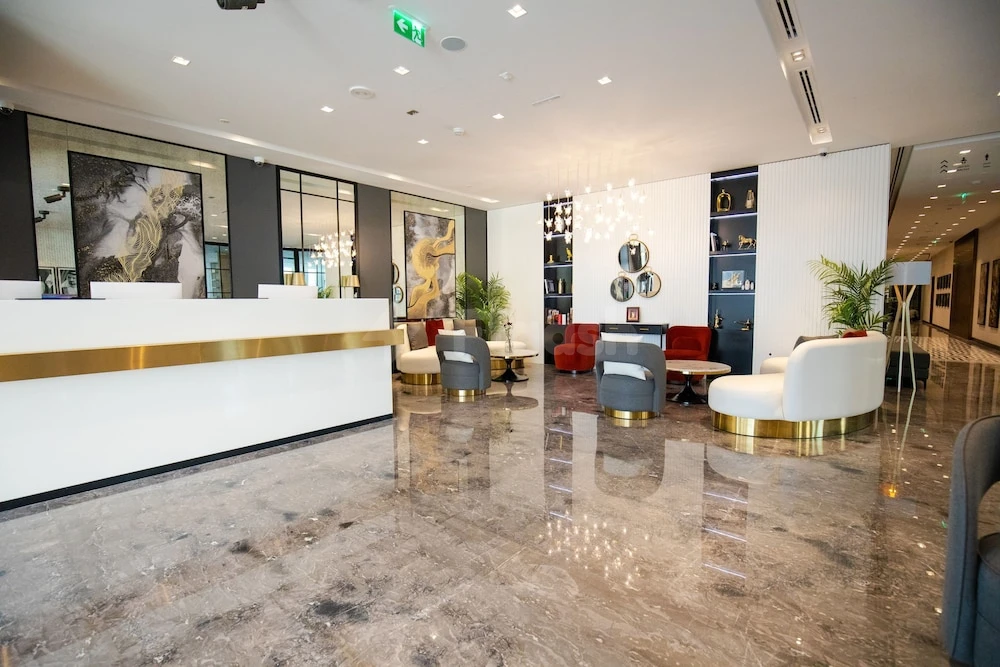 Lobby at Rose Executive, Dubai, with marble floors and gold-accented reception desk
