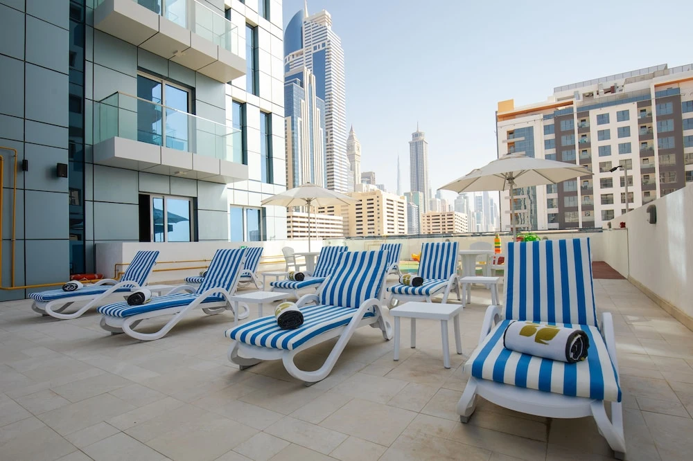 Rooftop terrace at Rose Executive, Dubai, with blue-and-white striped loungers and city skyline backdrop