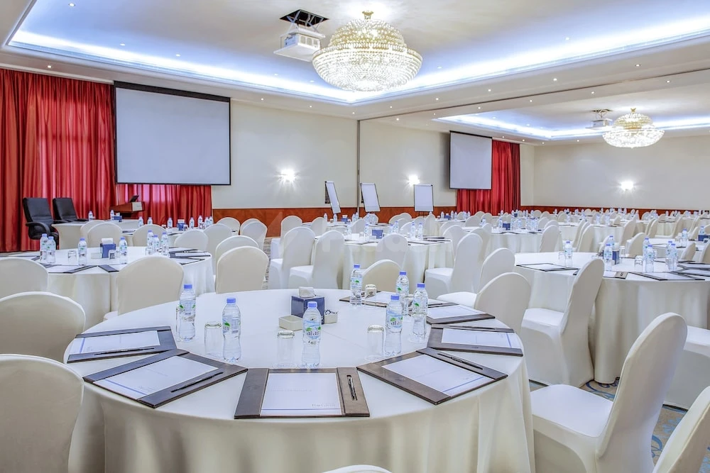 Banquet hall at Fujairah Rotana Resort & Spa, Fujairah, with round tables draped in white linens and crystal chandeliers
