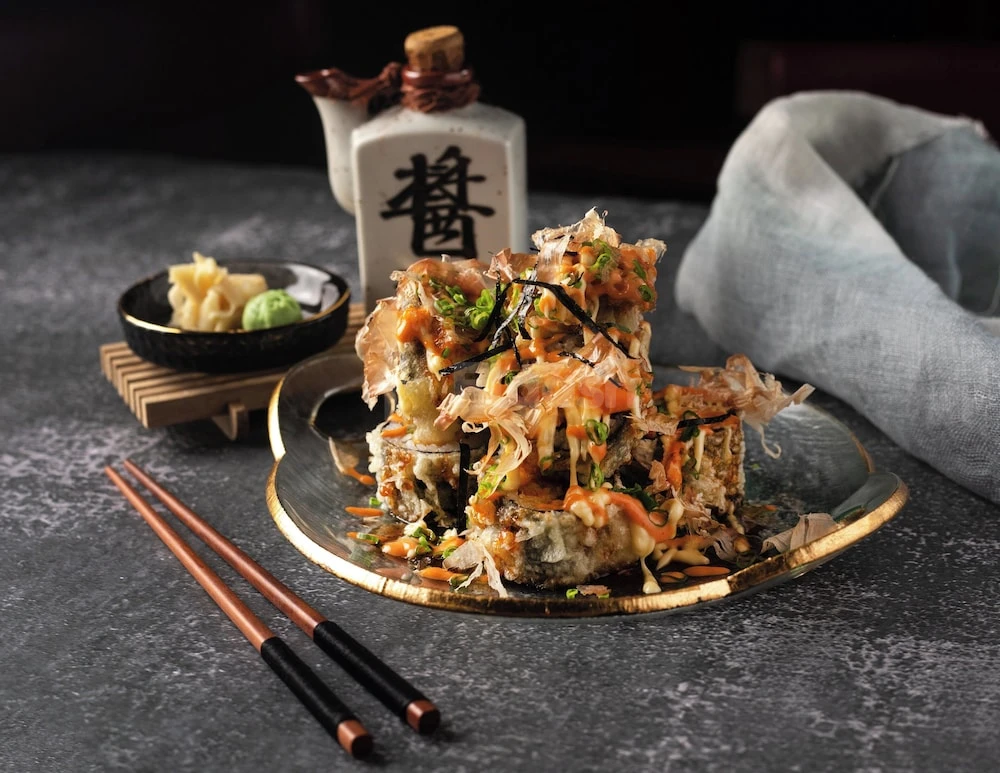 Sushi platter at Millennium Place Marina, Dubai, with golden-rimmed plate and wooden chopsticks
