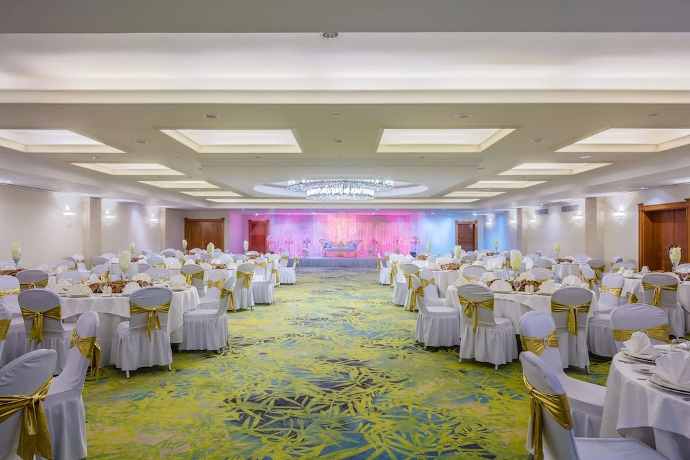 Banquet hall at Coral Beach Resort, Sharjah, with white draped tables and gold sashes on chairs over vibrant